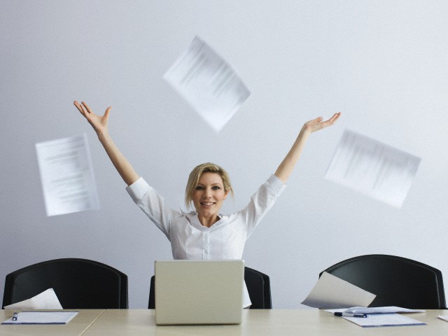 Businesswoman in office throwing paperwork into air