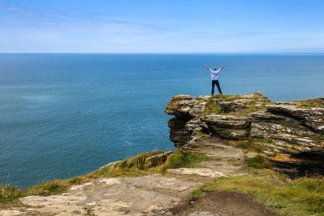 United Kingdom, England, Cornwall, Tintagel, North Coast, Tourist standing on rock