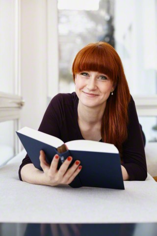 Young redheaded woman reading a book