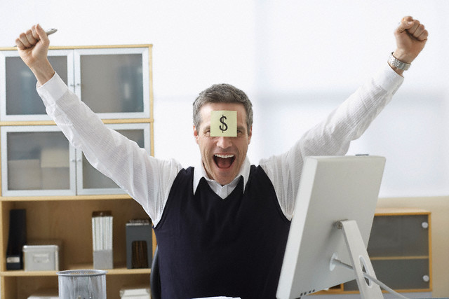 Businessman Sitting at Desk with Self Adhesive Note on Forehead